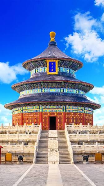 Vista frontal del Templo del Cielo, un imponente edificio circular tradicional chino con tejados azules escalonados y estructura roja,